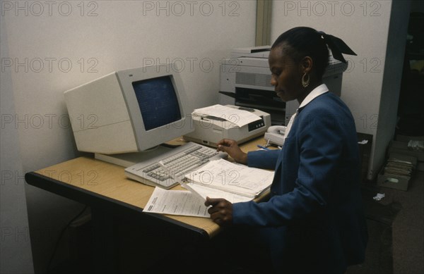 BOTSWANA, Computers, "Smartly dressed woman working on computer at office desk with printer, telephone and photo copier."