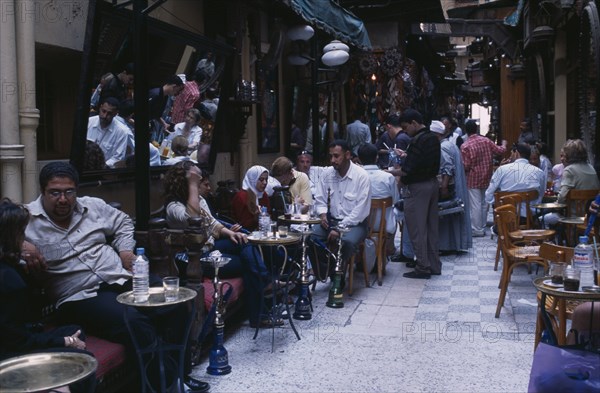 EGYPT, Cairo Area, Cairo, Fishawi’s coffee house in the Khan el-Khalili bazaar with men and women sitting at tables with water pipes used for smoking sheesha or hubble bubble.