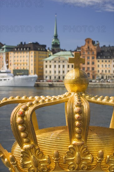 SWEDEN, Stockholm, Close-up of an ornamental crown on Skeppsholmsbron with Gamla Stan in the background.