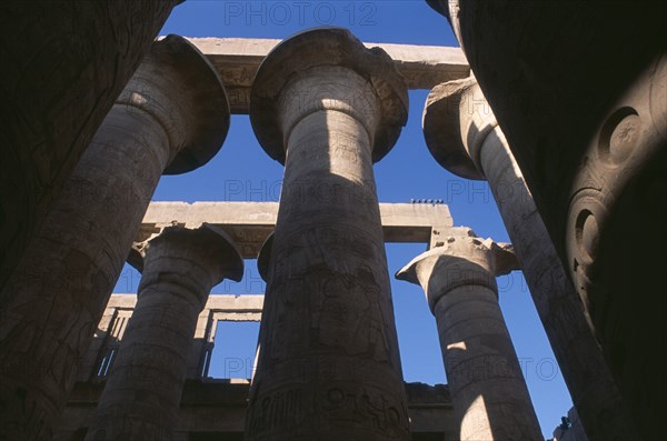 EGYPT, Nile Valley, Karnak, Temple Of Amun. Coloumns in the Great Hypostyle Hall. Angled view looking up through coloumns towards blue sky