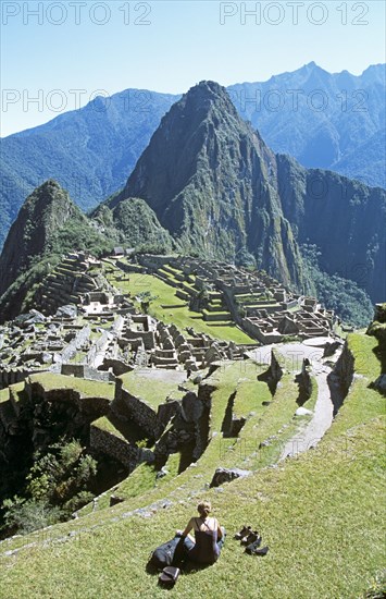 PERU, Cusco Department, Machu Picchu, "Inca ruins, terraces, visitor sitting on terrace, and Huayna Picchu."