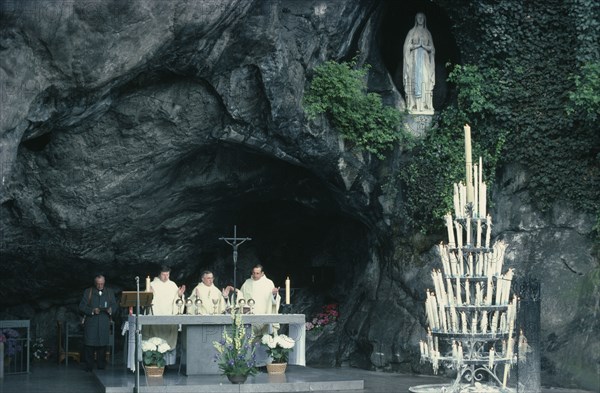 FRANCE, Midi-Pyrenees, Hautes-Pyrenees, Lourdes.  Priests conducting service at cave shrine in pilgrimage centre.