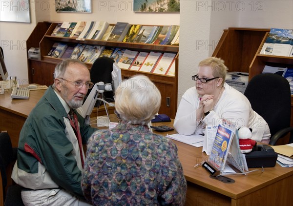 ENGLAND, West Sussex, Chichester, Male and female customer in a Travel Agents office discussing their holiday arrangements with a female travel consultant