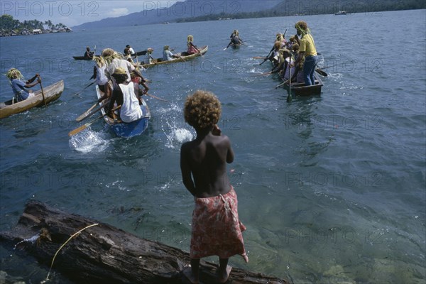PACIFIC ISLANDS, Melanesia, Solomon Islands, "Malaita Province, Lau Lagoon.  Child watching wedding party depart by canoe.  Note rafia head dresses of rowers."