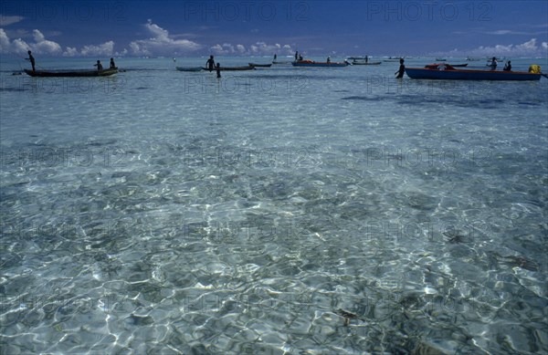 PACIFIC ISLANDS, Melanesia, Solomon Islands, "Malaita Province, Lau Lagoon. Distant fishing team and boats.  Expanse of turquoise sea with light reflections in foreground and blue sky."