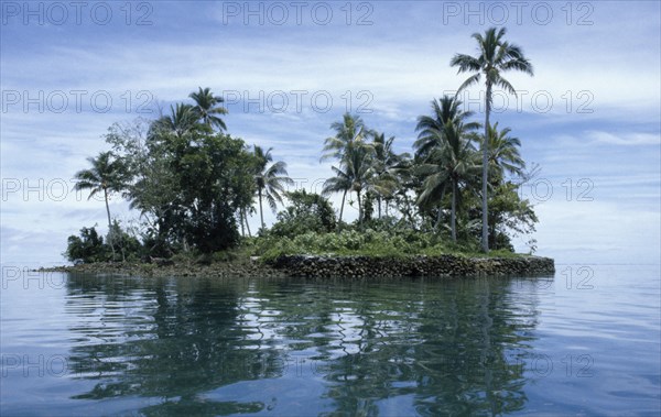 PACIFIC ISLANDS, Melanesia, Solomon Islands, "Malaita Province, Lau Lagoon.  Rocky (man made?) islet with palm trees and vegetation reflected in rippled water in foreground."