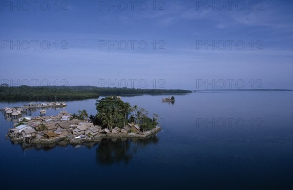 PACIFIC ISLANDS, Melanesia, Solomon Islands, "Malaita Province, Lau Lagoon, Foueda Island.  Artificial man made island and thatched houses, some on stilts with mainland covered by dense forest beyond. "