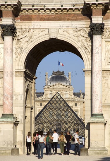 FRANCE, Ile de France, Paris, People walking from the Jardin des Tuileries through the Arc de Triomphe du Carrousel towards the pyramid entrance to the Musee du Louvre