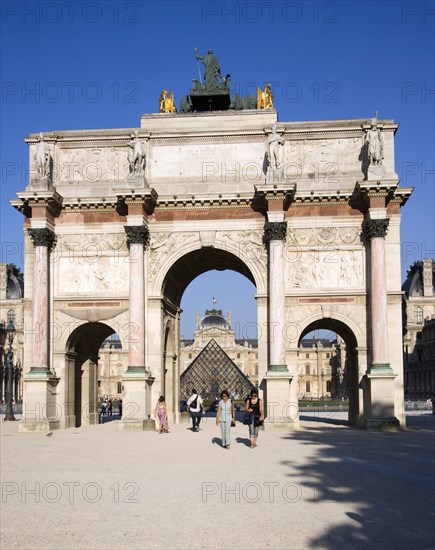 FRANCE, Ile de France, Paris, People walking from the Jardin des Tuileries through the Arc de Triomphe du Carrousel towards the pyramid entrance to the Musee du Louvre