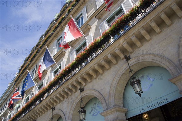 FRANCE, Ile de France, Paris, The five star Hotel Le Meurice in the Rue de Rivoli with red geraniums in window boxes on the balconies above the pavement arches beside flags of nations of the world