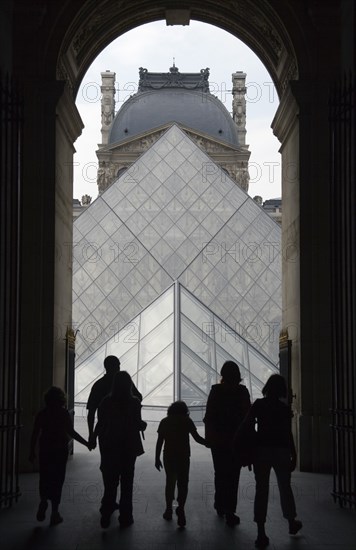 FRANCE, Ile de France, Paris, Tourist family passing through the Richelieu wing of the Louvre Museum heading towards the Pyramid entrance