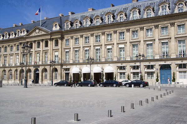 FRANCE, Ile de France, Paris, Limousines parked at the front of the Ritz Hotel in Place Vendome with the French Tricolour flying from a flagpole above the Ministry of Justice next door