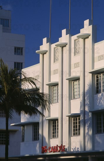 USA, Florida, Miami, South Beach. Ocean Drive. The Carlyle Hotel seen in early morning light with a palm tree casting a shadow on the exterior