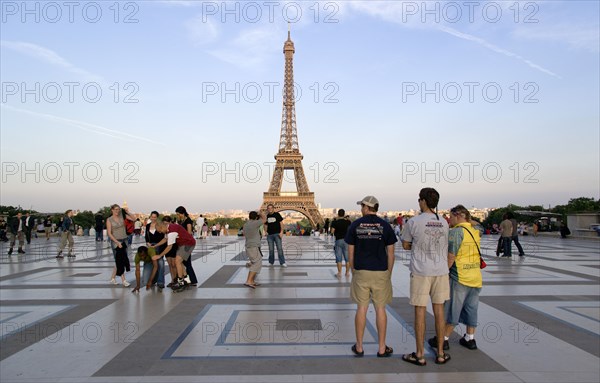 FRANCE, Ile de France, Paris, Young tourists in the main square of the Palais Chaillot at dusk with the Eiffel Tower in the distance