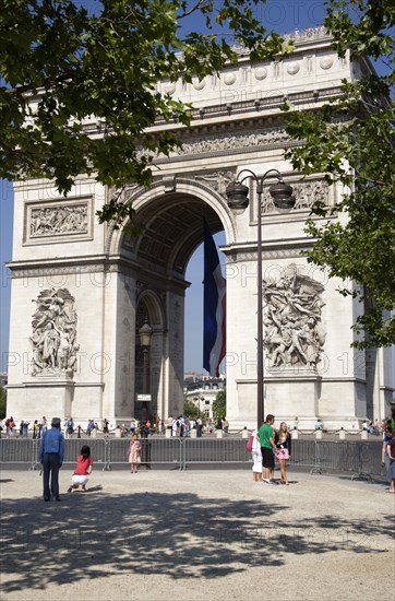 FRANCE, Ile de France, Paris, Tourists in the shade of trees in the Place de Charles de Gaulle looking at the Arc de Triomphe