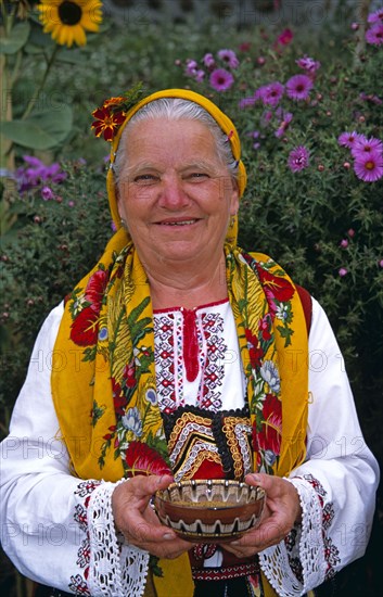 BULGARIA, Dobarsko, "Dobarski Babi Folk Group, member of folk group holding bowl of salt."