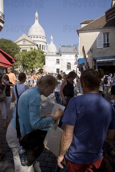 FRANCE, Ile de France, Paris, Montmartre Place du Tertre a square beside the church of Sacre Couer with a tourist discussing a painting with an artist vendor