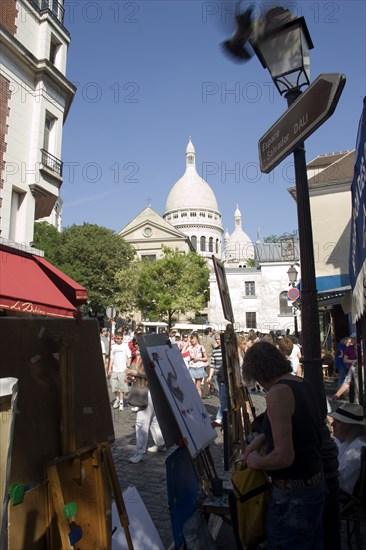 FRANCE, Ile de France, Paris, Montmartre Tourists walking past artists painting in Place du Tertre square beside the Church of Sacre Couer