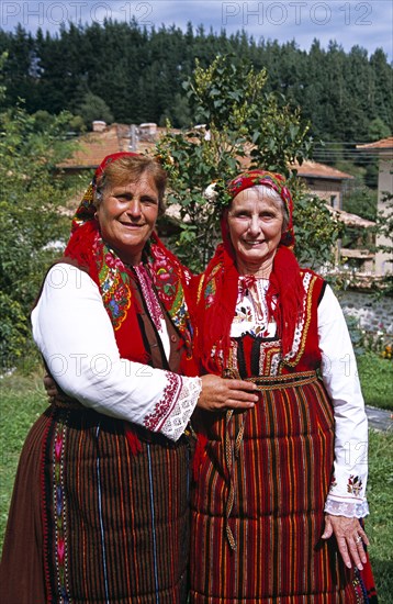 BULGARIA, Dobarsko, "Member of Dobarski Babi Folk Group, and tourist on right, in national costume"