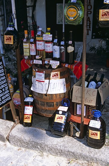 BULGARIA, Melnik., "Display of wine bottles, barrel, and containers outside shop."