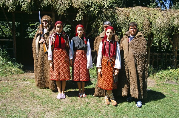 BULGARIA, Pirin Mountain, Chalin Valog, Girls dressed in Bulgarian national costume and men dressed as hunters.