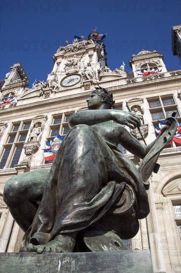 FRANCE, Ile de France, Paris, One of several female bronze statues in front of the Hotel de Ville town hall adorned with French tricolour flags