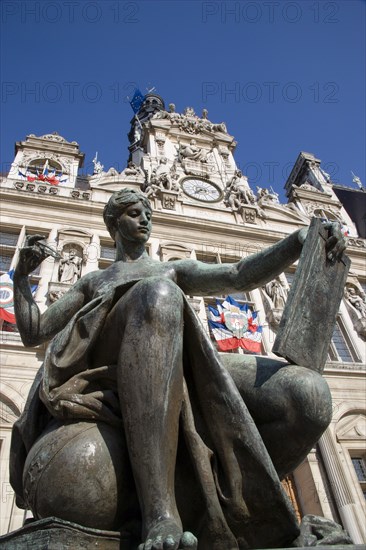 FRANCE, Ile de France, Paris, One of several female bronze statues in front of the Hotel de Ville town hall adorned with French tricolour flags
