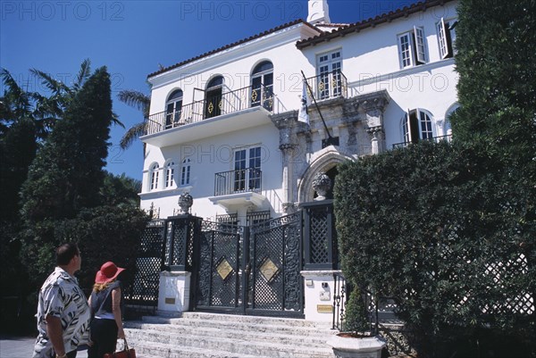 USA, Florida, Miami, South Beach. Ocean Drive. Gianni Versace’s Mansion Casa Casuarina. Man and woman viewing the front exterior from the bottom of entrance steps