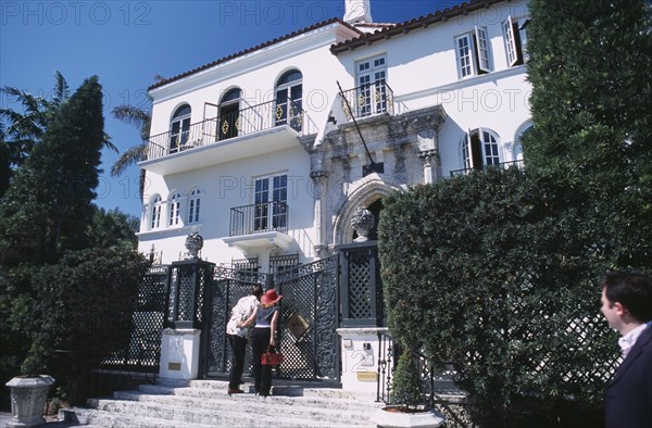 USA, Florida, Miami, South Beach. Ocean Drive. Gianni Versace’s Mansion Casa Casuarina.  Man and woman peering through the gate at main entrance