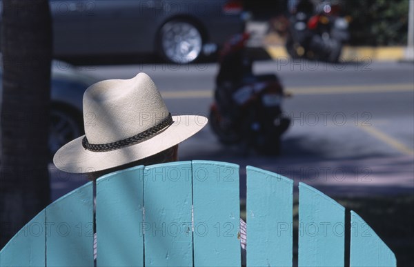 USA, Florida, Miami, South Beach. Ocean Drive. The head of a man wearing a Panama hat seen above the top of a seat watching people and traffic go by