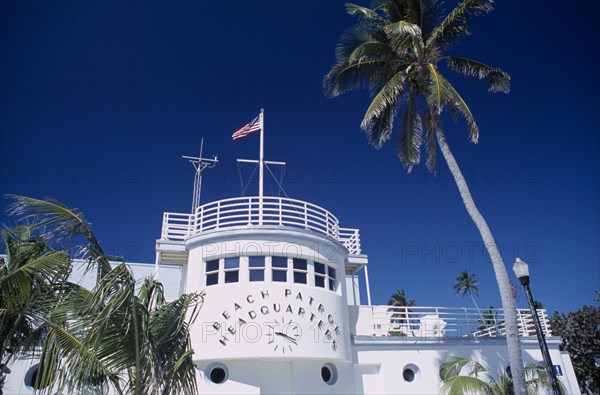 USA, Florida, Miami, South Beach. Ocean Drive. Beach Patrol Headquarters building with an American flag flying from the roof surrounded by palm trees