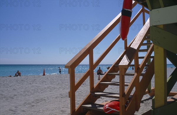 USA, Florida, Miami, South Beach. Ocean Drive. Lifeguard station on sandy beach with view of steps and red rescue floats. Sunbathers on sand near turquoise sea