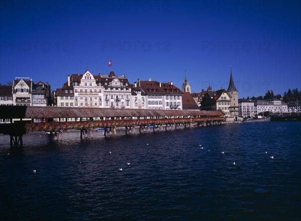 SWITZERLAND, Lucerne Central, Lucerne, Kappelbrucke flower decked covered bridge spanning across The River Reuss.