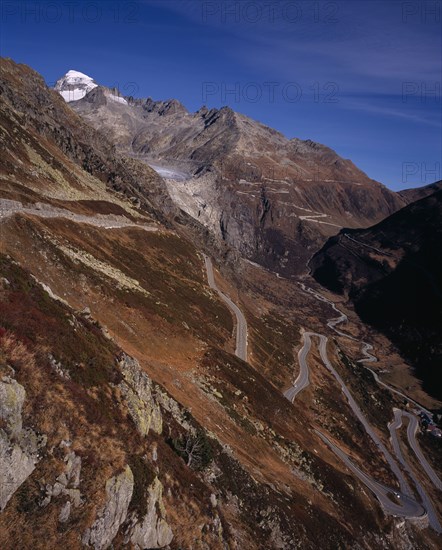 SWITZERLAND, Valais, Grimsel Pass, The Upper Rhone Valley with the Grimsel Pass in the foreground. The distant Furka Pass seen winding above. Snow covered Galenstock Mountain 3586metres  (11744ft ) on the left