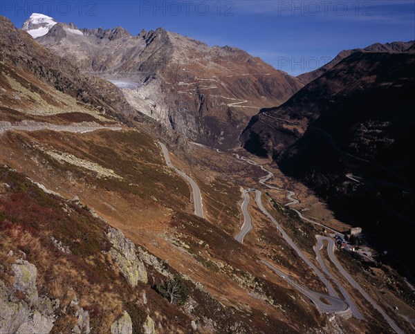 SWITZERLAND, Valais, Grimsel Pass, The Upper Rhone Valley with the Grimsel Pass in the foreground. The distant Furka Pass seen winding above. Snow covered Galenstock Mountain 3586metres  (11744ft ) on the left