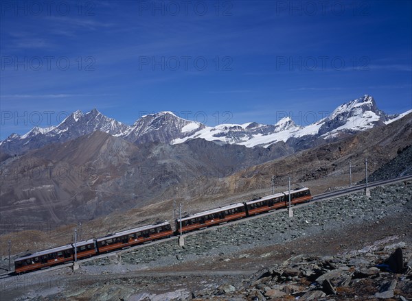 SWITZERLAND, Valais, Zermatt, "Gornegrat Railway with train traveling past snow capped mountains left to right, Oberrothorn 3414metres   ( 11180ft  ) and Fluehorn 3317metres ( 10863ft )"