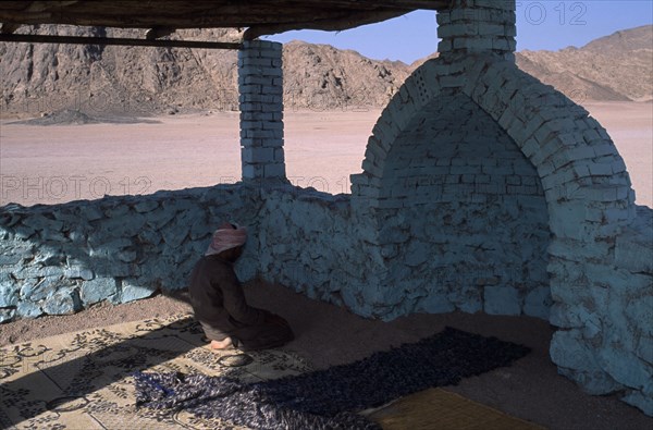 EGYPT, Religion, Islamic, Bedouin man worshipping in Eastern Desert Mosque made with brick and painted turquoise