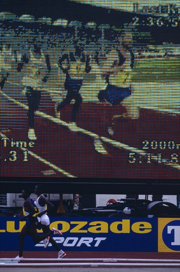 20085195 SPORT Athletics Running Male athletes at a meeting running past an electronic viewing screen