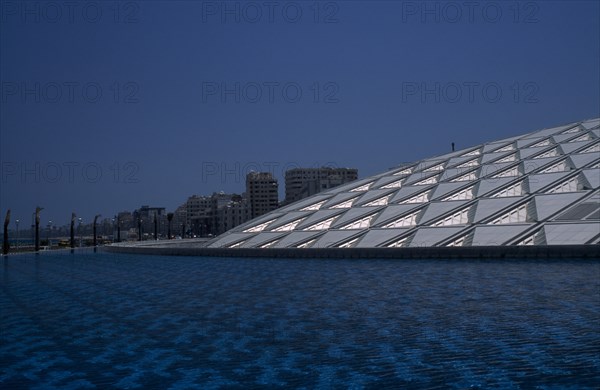 EGYPT, Nile Delta, Alexandria, Bibliotheca Alexandrina modern library exterior with detail of interlocking panelled roof seen from across pool of water