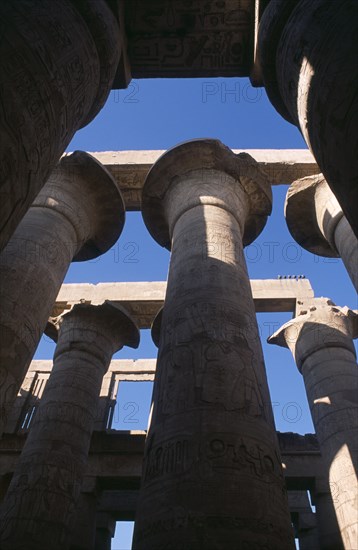 EGYPT, Nile Valley, Karnak, Temple Of Amun. Coloumns in the Great Hypostyle Hall. Angled view looking up through coloumns towards blue sky