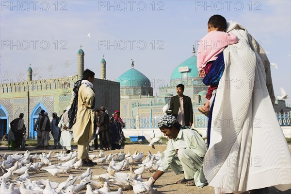 AFGHANISTAN, Mazar-I-Sharif, "Family feeding famous white pigeons at Shrine of Hazrat Ali (who was assissinated in 661) This shrine was built here in 1136 on the orders of Seljuk Sultan Sanjar, destroyed by Genghis Khan and rebuilt by Timurid Sultan Husain Baiqara in 1481, since restored. The shrine is famous for its white pigeons, it is said the site is so holy that if a grey pigeon flies here it will turn white within 40 days"