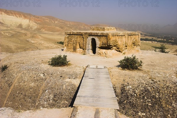 AFGHANISTAN, Samangan Province, Top-I-Rustam, "2km south of the centre of Haibak, Wooden bridge across chasm leading to Buddhist stupa carved out of rock known as Top-I-Rustam (Rustam's throne) an early burial mound that contained relics of the Buddha, part of a stupa-monastery complex carved from rock dating from the Kushano-Sasanian period 4th-5th century AD. The stupa is situated above caves where the monks lived"