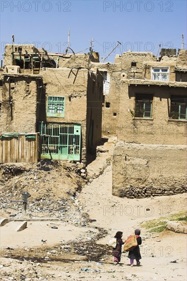 AFGHANISTAN, Ghazni, "Children walk with sacks over their shoulders toward houses inside the ancient walls of Citadel