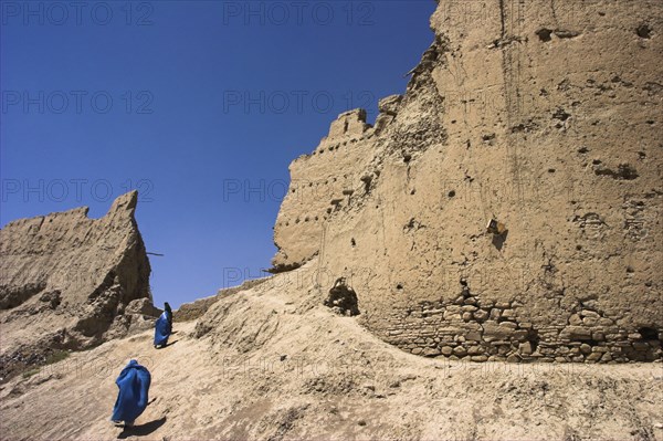 AFGHANISTAN, Ghazni, Ladies wearing burqua walk near ancient walls of Citadel destroyed during First Anglo Afghan war since rebuilt still used as a military garrison Jane Sweeney