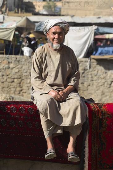 AFGHANISTAN, Kabul, Rug seller sit on walls of Kabul river