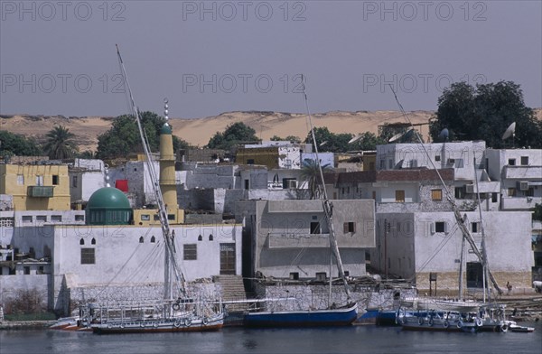 EGYPT, Near Aswan, Elephantine Island, Nile River Nubian Village with boats moored on water next to waterfront buildings.