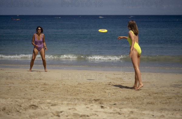 20085230 SPORT Games Frisbee Two women wearing bathing costumes playing Frisbee on sandy beach next to the sea in St Ives  Cornwall  England