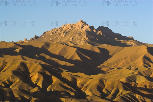 AFGHANISTAN, Bamiyan Province, Bamiyan, Late afternoon sun glows on mountains near the empty niche where the famous carved Budda once stood (destroyed by the Taliban in 2001)
