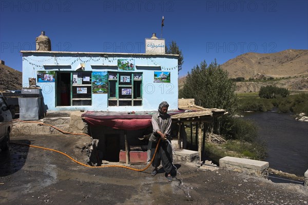 AFGHANISTAN, Hejigak pass, "Between Kabul and Bamiyan, after Hejigak pass, Man hoseing road infront of his chiakana (tea house) to stop the dust blowing in"