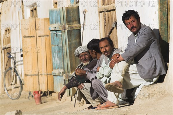 AFGHANISTAN, between Yakawlang and Daulitiar, Syadara, Men sit outside shop in early morning sunshine